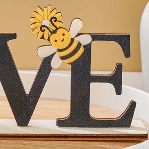 Close-up detail of cute bumblebee and sunflower on rustic wooden LOVE letter ornament