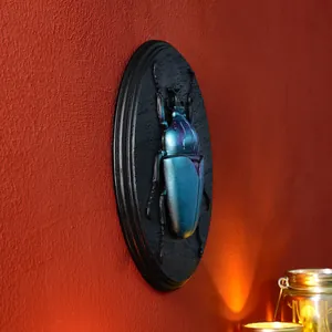 Close-up of vintage resin beetle relief wall decor with iridescent teal finish on red wall