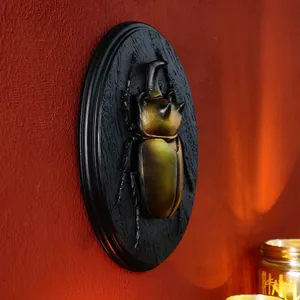 Detailed macro view of a vintage resin beetle relief wall hanging on a red textured background