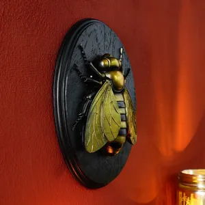 Detailed side view of a vintage golden bee resin wall relief on a black plaque
