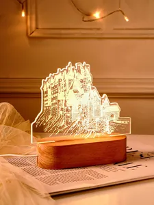 Nahaufnahme eines 3D-Schloss-Acryl-Nachtlichts mit warmem Holzsockel auf einem Tisch.