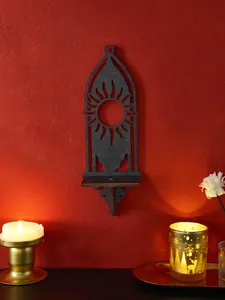 Mensola da muro decorativa in legno nero a forma di sole su sfondo di parete rossa