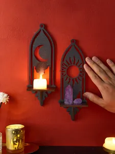 Dettaglio di mensole a muro in legno nero con sole e luna per cristalli e candele profumate.