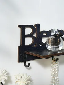 Dettaglio ravvicinato di mensola a muro in legno nero con scritta Blessed e gancio