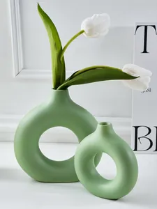 Set van twee groene keramieken donutvazen met witte tulpen in minimalistisch decor