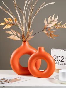 Moderne oranje O-vormige keramische vazen met gedroogde decoratieve bladeren detail