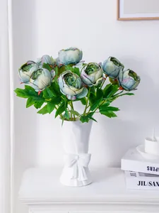 Elegantes peonías artificiales en jarrón blanco con lazo para decorar.