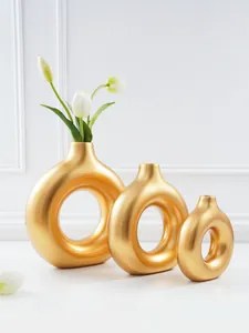Detailweergave van drie minimalistische gouden donutvazen in verschillende maten.