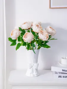 Elegantes peonías artificiales color melocotón en jarrón blanco con lazo para decoración