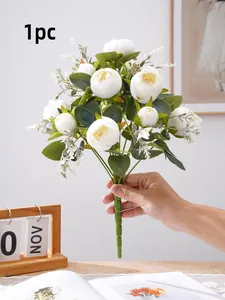 Mano sosteniendo un ramo detallado de peonías artificiales blancas para decoración