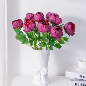Elegantes peonías artificiales moradas en un jarrón blanco con lazo para decoración