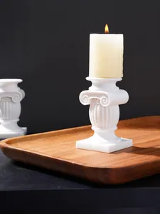 Vista detallada de un candelabro clásico de columna romana blanca en una bandeja de madera.