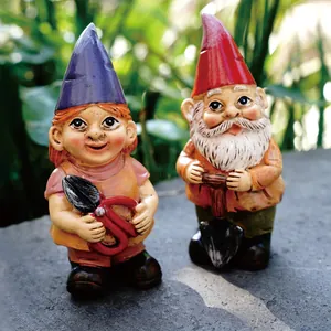 Close-up of two miniature garden gnome figurines holding garden tools in outdoor setting