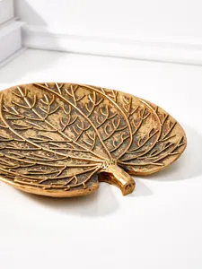 Gros plan d'un décor mural en forme de feuille tropicale en résine or antique