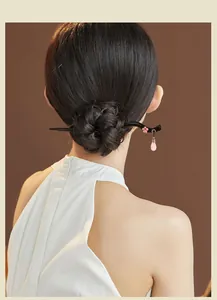 Detailansicht eines Vintage-Haarstabs aus Sandelholz mit rosa Kristallquaste im Dutt