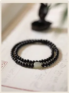 Detalle de una pulsera minimalista de cuentas de ébano con una cuenta de jade Hetian pulida.