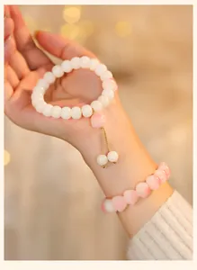 Elegant white Bodhi root bead bracelet and cute pink cat paw charms shown on woman's hand
