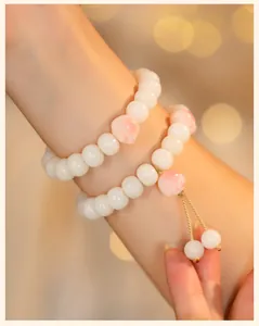 Detailed macro view of white Bodhi root bead bracelet featuring a cute pink cat paw charm.
