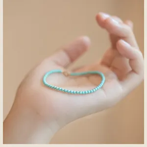 Close-up view of 2mm thin natural turquoise beaded bracelet with a 14k gold clasp