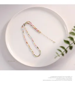 Close-up of a natural colorful tourmaline beaded necklace on a white ceramic plate.