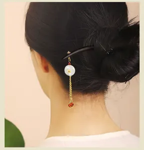 Elegante Vintage Sandelholz-Haarnadel mit weißem Anhänger und goldenen Quasten im Dutt