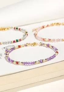 Detalle macro de una delicada pulsera de cuentas de amatista púrpura con detalles dorados en libro