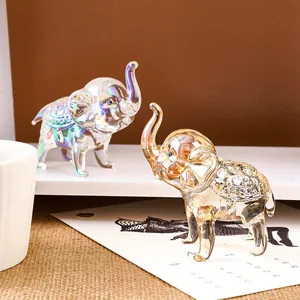 Par de figuras de elefantes de cristal en acabados iridiscentes y ámbar sobre escritorio.