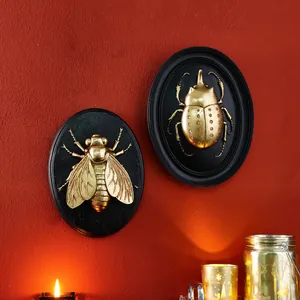 Detailed macro view of vintage golden resin insect reliefs on black wall plaques.