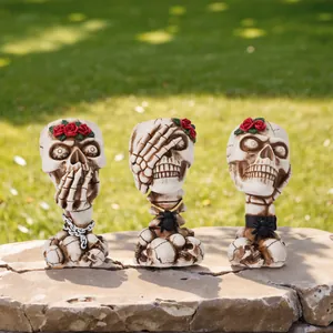Three gothic skull figurines acting as brush holders or pots with red rose accents