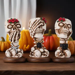 Close-up of three vintage skull makeup brush holders with rose and spider decorations