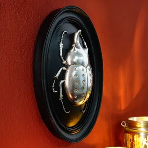 Close-up of a vintage silver beetle resin wall relief mounted in a black frame.