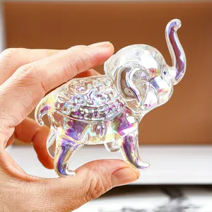 Primer plano de un adorno de elefante de cristal iridiscente sostenuto para escala