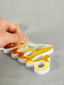 Close-up of peeling protective film from golden acrylic candy sign ornament