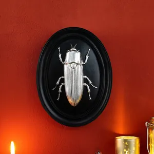 Detail view of a vintage silver beetle relief on a black resin oval wall plaque decor