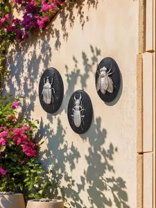 Dettaglio di tre decorazioni murali con rilievi di scarabei argentati su parete soleggiata
