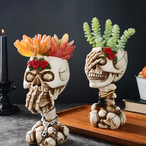 Detail view of gothic skeleton skull planters with red roses and decorative succulent plants