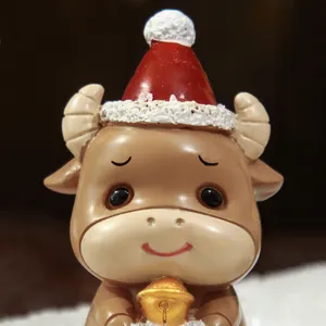 Nahaufnahme einer niedlichen Harzstierfigur mit roter Weihnachtsmütze und goldener Glocke.