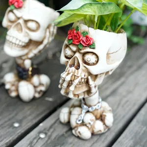 Detail view of vintage gothic skull planter with red roses and skeletal hand design
