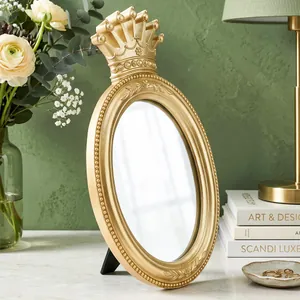 Detail of a vintage golden crown oval tabletop vanity mirror in a stylish lifestyle setting