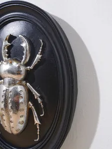 Dettaglio ravvicinato di rilievo scarabeo argento 3D su decorazione murale ovale