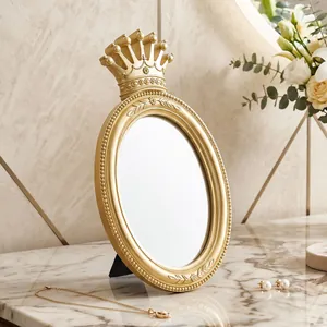 Close-up shot of a vintage gold crown oval tabletop makeup mirror on a luxury marble vanity