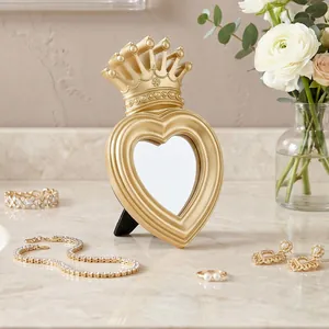 Detailed view of a vintage gold heart-shaped mirror with an ornate crown top.