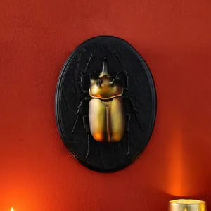 Vintage 3D golden beetle resin wall relief on black oval base with red wall backdrop