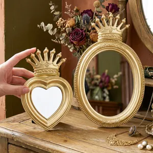 Macro detail showing vintage gold crown heart and oval makeup mirrors on wooden vanity
