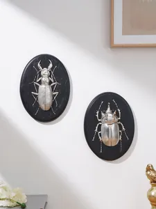 Primo piano di targhe murali in rilievo a scarabeo argento su muro bianco