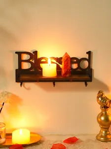 Primo piano della mensola a muro in legno nero Blessed con ganci in luce calda di candela