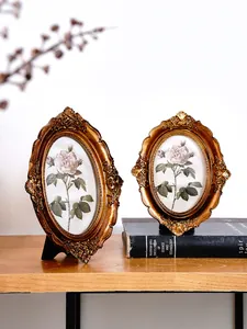 Detailed view of ornate bronze resin photo frames with vintage rose prints on a bookshelf