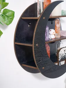 Close-up of black moon-shaped wooden wall shelf with decorative sheep figurine