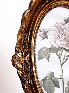 Detailed view of the intricate bronze-gold ornate carvings on a vintage resin art frame.