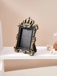 Vintage black and gold crown relief picture frame displayed on a white shelf